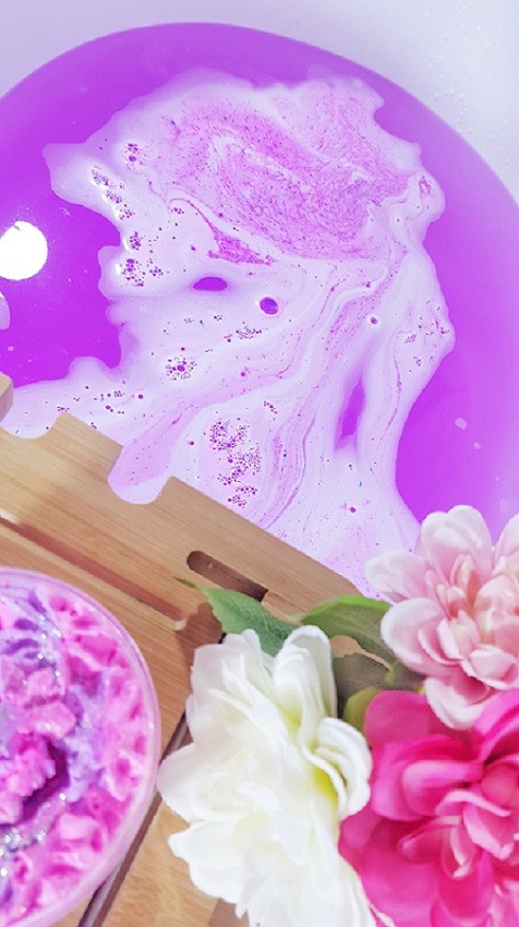 Bombas para baño efervescente. Imagen de Utilizar bomba de baño en una bañera, color morado llamativo.