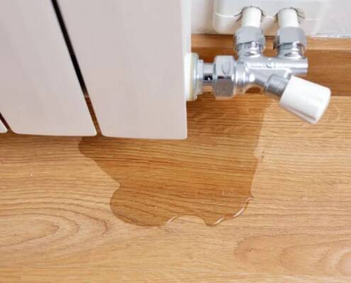 Agua goteando sobre el suelo debido a una fuga de agua de un radiador con llaves con entre-eje central