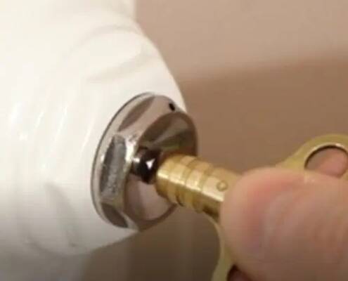 Hombre vaciando el aire de un radiador hidráulico con una llave purgadora