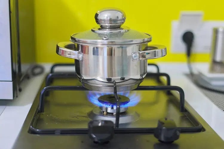 Una olla en un quemador en cocina de gas con tapa cerrada