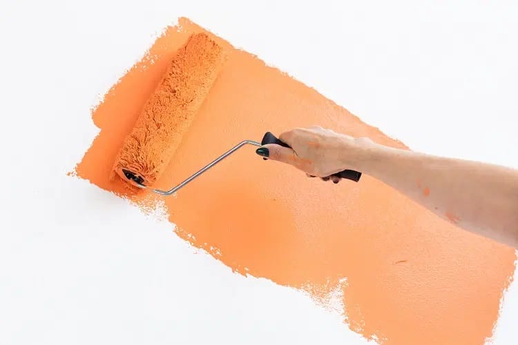 Pintura de color cálido siendo pintada sobre una pared de cocina con un rodillo