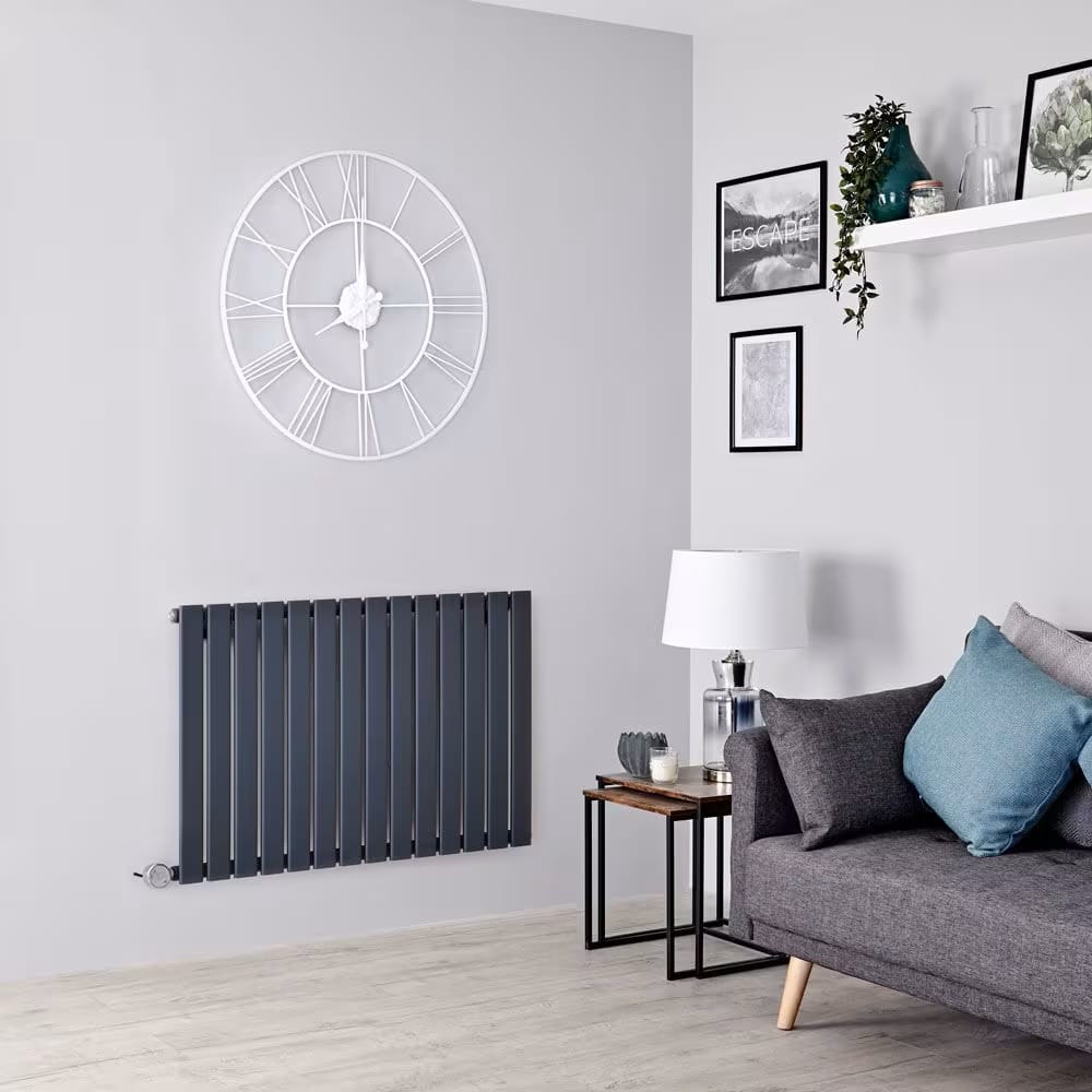 Imagen de un radiador horizontal eléctrico mural moderno sobre la pared con paneles planos verticales en salón minimalista con sofá gris y mesita pequeña